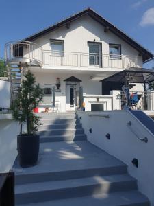 a white house with stairs and a potted plant at Design Apartments Tomelana in Ličko Petrovo Selo