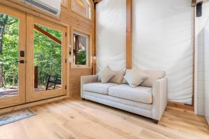 a living room with a white couch and a sliding glass door at Tree Farm Duo - Best of the Ozarks in Walnut Shade