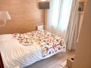 a bedroom with a bed with a floral comforter at Les copains d'amour in Guérande