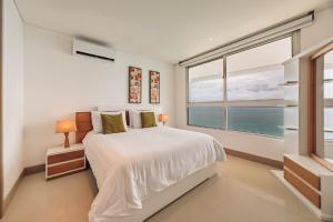 een witte slaapkamer met een bed en een groot raam bij Palmetto Beach by MOME in Cartagena +159 foto's