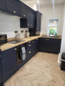a kitchen with black cabinets and a wooden floor at Relaxing Seaside Stay 3-Bed Home Minutes from Hythe Beach in Hythe +22 photos