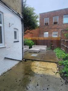 a patio with two benches in front of a building at Relaxing Seaside Stay 3-Bed Home Minutes from Hythe Beach in Hythe