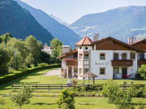 a building in a field with mountains in the background at Anewandterhof in Brunico