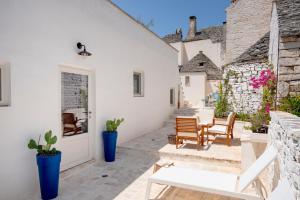 a patio with a white door and chairs and plants at Trulli Lithos Suite in Alberobello