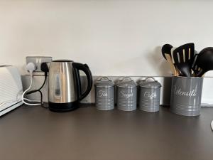 a row of coffee pots and utensils on a counter at LUX 2bed City Centre and AO Arena Free Parking Modern Apt in Manchester +22 photos