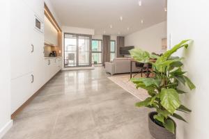 a living room with white walls and a large plant at Deluxe Apartment on Granary Island with Parking - Granaria I & by Noclegi Renters in Gdańsk