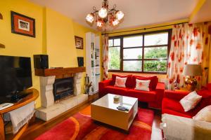 a living room with a red couch and a fireplace at Espectacular villa con piscina in Boó de Piélagos