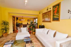 a living room with yellow walls and white couches at Espectacular villa con piscina in Boó de Piélagos +33 photos