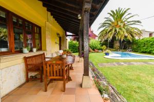 a patio with a table and chairs and a yard at Espectacular villa con piscina in Boó de Piélagos