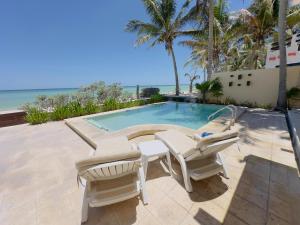 a patio with two chairs and a swimming pool at Sunset Mompracem in Chicxulub, Yucatan in Chicxulub +33 photos