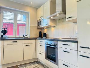 une cuisine avec des armoires blanches et une cuisinière dans l'établissement Hus bei de Dün, à Böhl