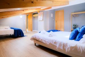 two beds in a room with blue walls and wooden ceilings at Ático Alfonso Amplio Céntrico Renovado 10 Pax in Zaragoza