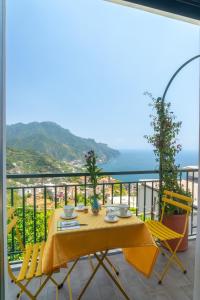 a yellow table and chairs on a balcony with the ocean at Mare Luna - Enchanting sea view apartment in Ravello