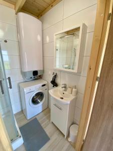 a small bathroom with a washing machine and a sink at Mile domki in Jarosławiec