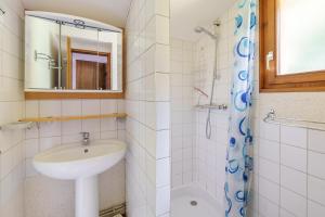 Un baño blanco con lavabo y ducha. en Chalet des cimes - Avec jardin, en La Bresse