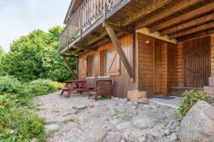 Una cabaña de madera con dos bancos y un balcón. en Chalet des cimes - Avec jardin, en La Bresse