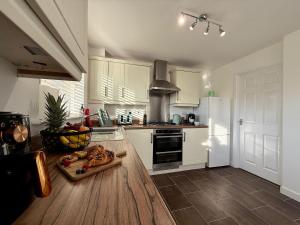 a kitchen with white cabinets and a chopping board on the floor at Spacious 5-Bed Home in Birstall - Sleeps 13 - Free Parking- WiFi - Patio - Garden - Meadow Views in Thurcaston
