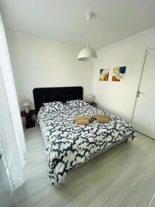 Un dormitorio con una cama con un edredón blanco y negro. en Les lauriers1, en La Rochelle 1 foto más