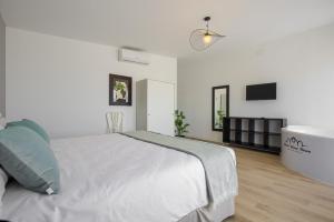 a white bedroom with a bed and a tv at Hotel Finca Biazu in Ocaña