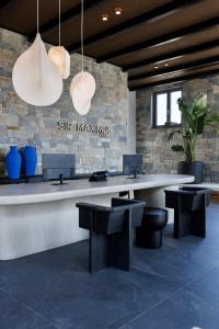 um saguão com mesa, bancos e luminárias pendentes em Maximus Mykonos em Platis Yialos Mykonos mais 107 fotografias