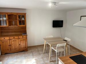 una cucina con tavolo, sedie e TV di La Cigalière - Appartement Rez-de-Jardin a Vallauris