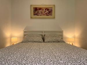 un letto in una camera da letto con due lampade e un quadro di La Cigalière - Appartement Rez-de-Jardin a Vallauris