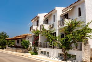 a white building with balconies on a street at FRINI APPARTMENTS in Kokkari