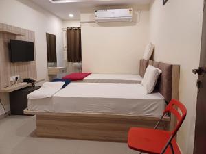 a bedroom with a bed and a red chair at Sahasra Sree Suites Inn in Hyderabad