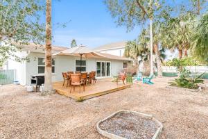 a backyard with a wooden deck with a table and chairs at Modern Coastal Home in Clearwater Beach