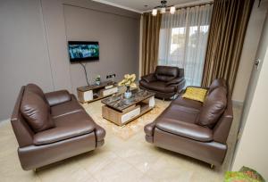 a living room with two leather chairs and a tv at Edrin Apartments in Kampala