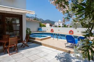 a swimming pool with chairs and a table next to a house at FRINI APPARTMENTS in Kokkari