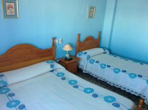 two beds in a room with blue walls at PENSIÓN EGEA 1 in Puerto de Mazarrón