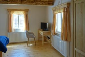 a bedroom with a desk with a television and two windows at Roubenka u kostela 