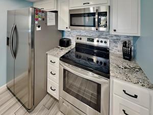 a kitchen with white cabinets and a stainless steel refrigerator at Sandy Shores in Port Aransas