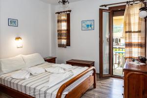 a bedroom with a bed and a sliding glass door at FRINI APPARTMENTS in Kokkari