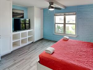 a bedroom with a red bed and a flat screen tv at Sandy Shores in Port Aransas +6 photos