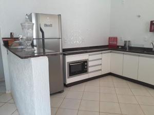 een keuken met een roestvrijstalen koelkast en een tegelvloer bij Casa Cachoeira Tororó in Brasilia