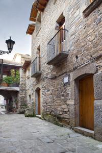 a stone building with a wooden door and a balcony at Casa Encuentra, en el Pirineo al lado de Ainsa in El Pueyo de Araguás