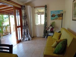 a living room with a yellow couch and a balcony at The Pool House in Saint Philip