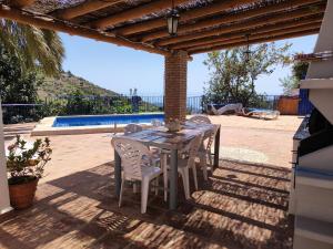 a wooden table and chairs under a pergola at Casa Carámbila in Cómpeta