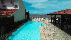 a swimming pool next to a building and the ocean at Rede Andrade Baía Dos Corais in Tamandaré