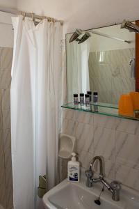 a bathroom with a sink and a shower curtain at FRINI APPARTMENTS in Kokkari +13 photos