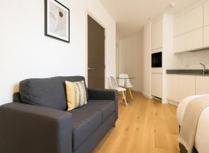 a living room with a couch and a kitchen at Bright Studio Flat - Walk to River Thames & Kingston Town in Surbiton