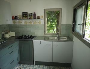a kitchen with a sink and a stove and a window at Lelieu Source, une chambre au jardin in Saint-Pons-de-Thomières