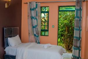 two beds in a room with a window at Muthiga Garden Resort Chaka in Nyeri