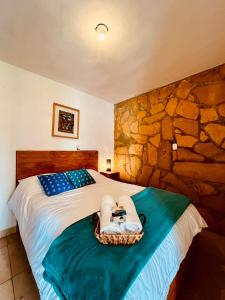 a bedroom with a bed with a stone wall at Gaia Guest House in San Cristóbal de Las Casas