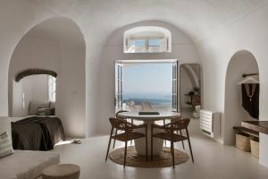 a room with a table and chairs and a bedroom at Aqua Luxury Suites by NOMÉE Hospitality Group in Imerovigli