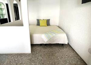 a small room with a bed with a yellow pillow at Suite con acceso a playa y vista espectacular in Acapulco