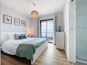a white bedroom with a bed and a large window at Atlantic Haven by Atlantic Holiday in Garajau
