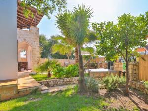 un jardin avec un palmier et un mur de pierre dans l'établissement Villa Yasemin, à Kaş